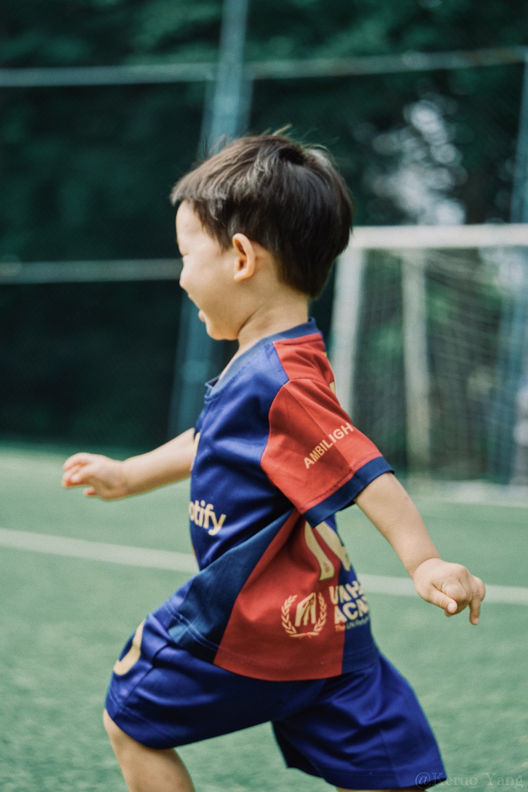 A boy in a red and blue kit running across the pitch — lead image